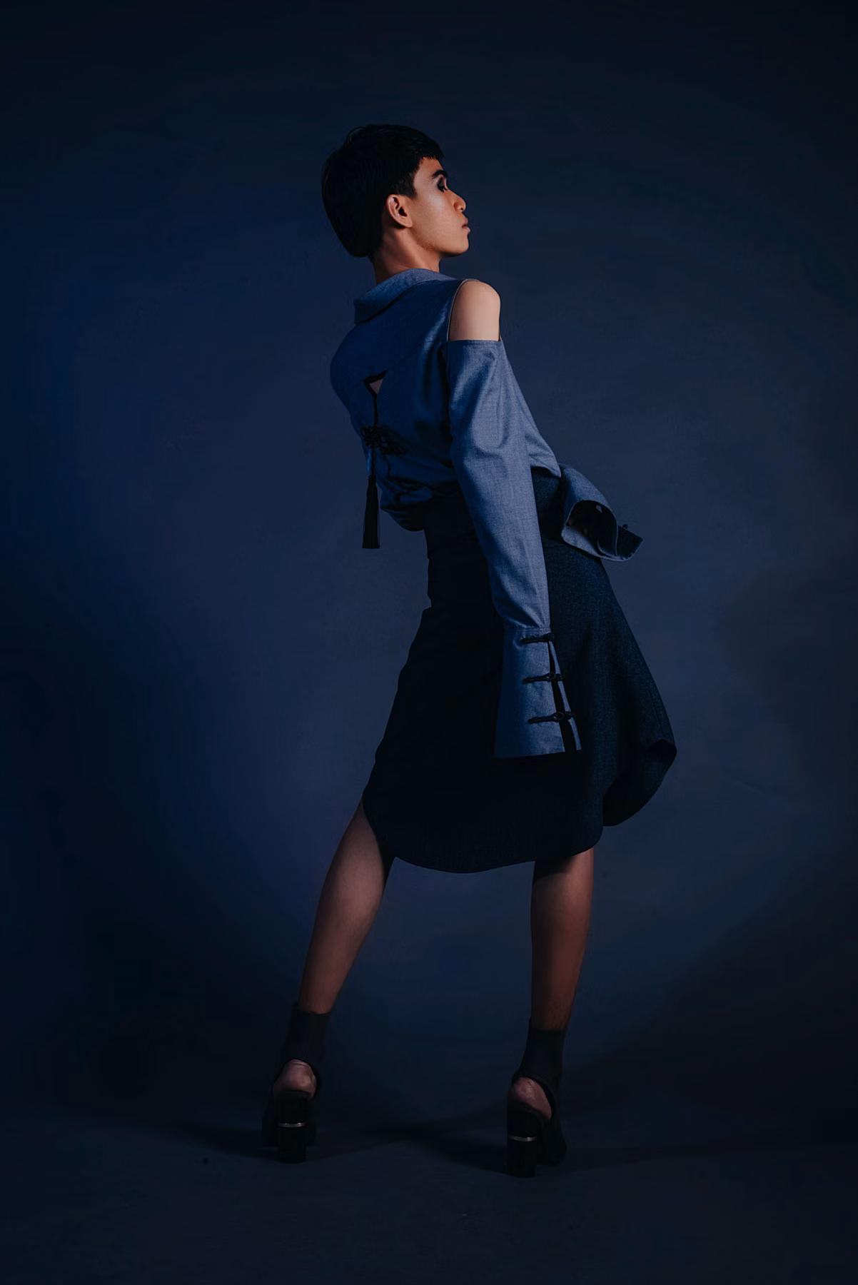 A sculptural navy outfit in dramatic side lighting